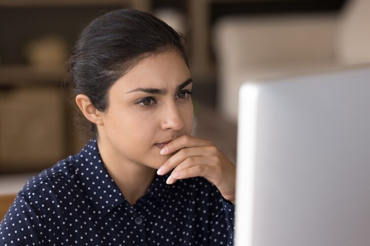 Pensive female professional working at computer from home