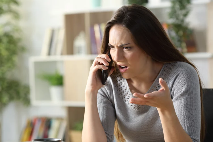 Angry woman calling arguing on phone at home