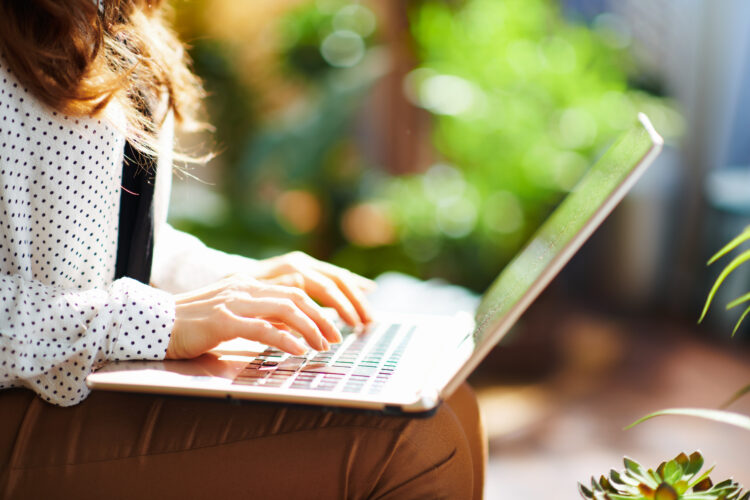 Stylish woman typing on laptop outdoors 