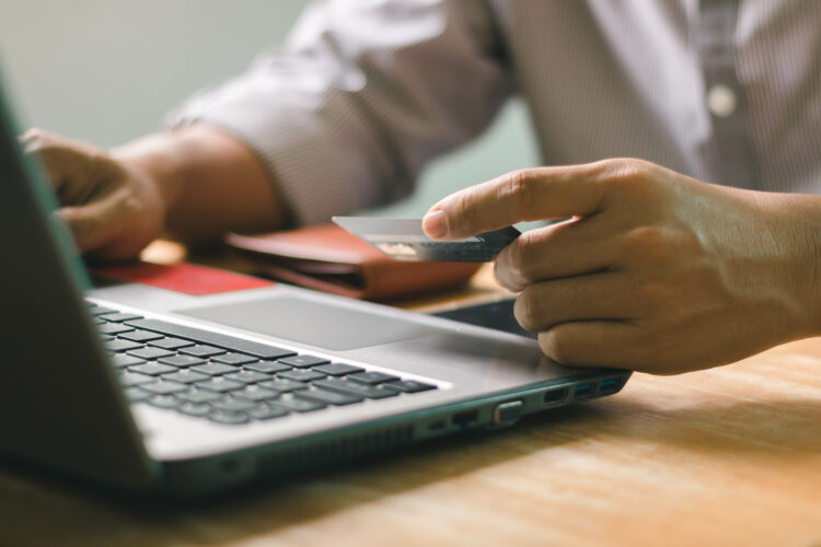 Businessman using laptop computer with a credit card making an online order. 