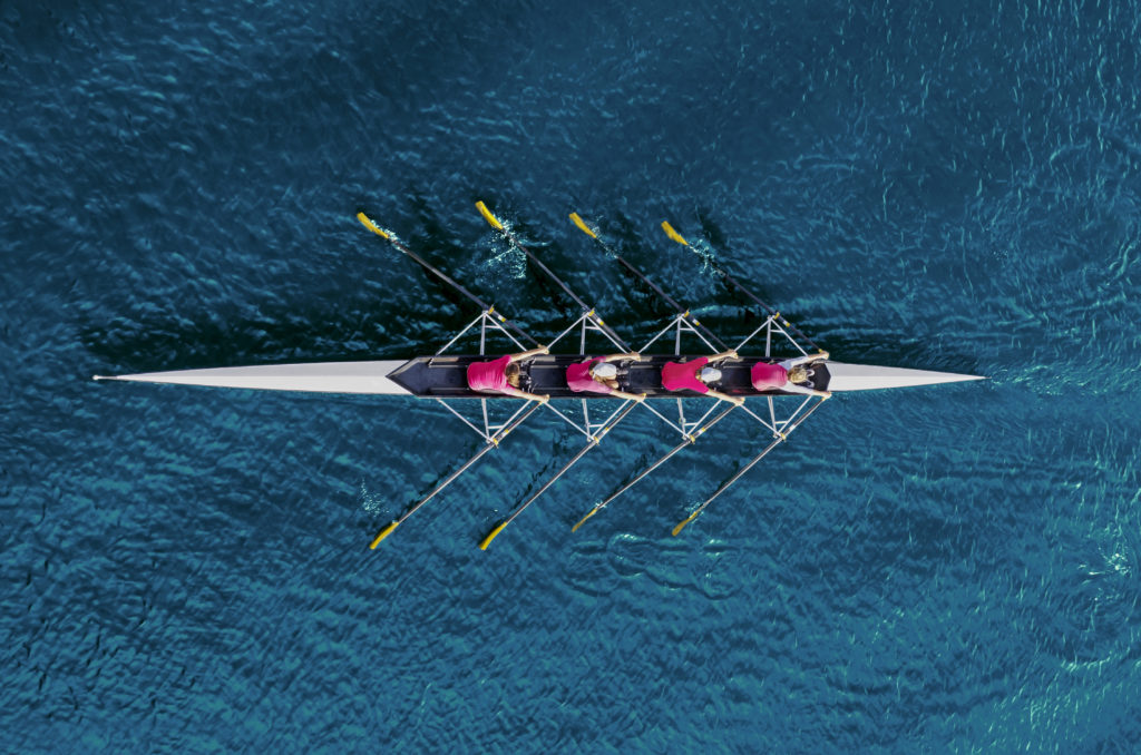 Women's rowing team on blue water, top view.