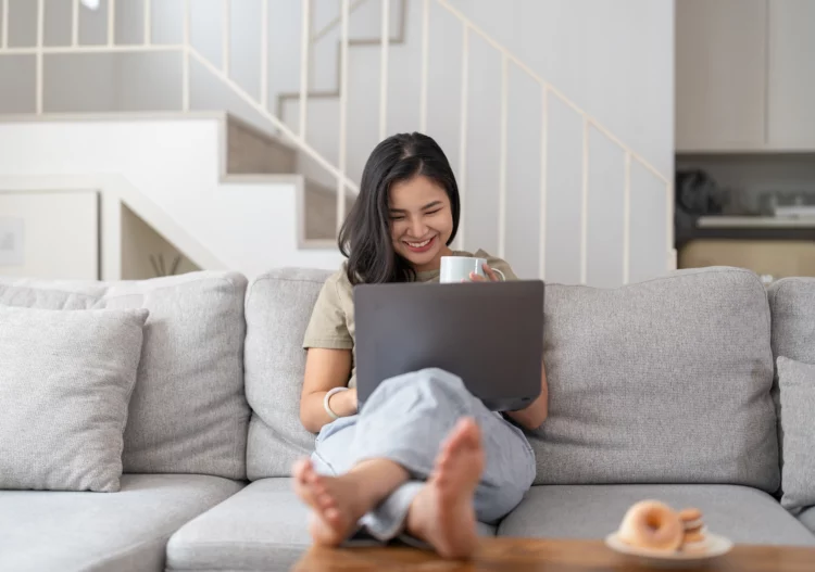 Happy young woman smiling while using laptop at house. 