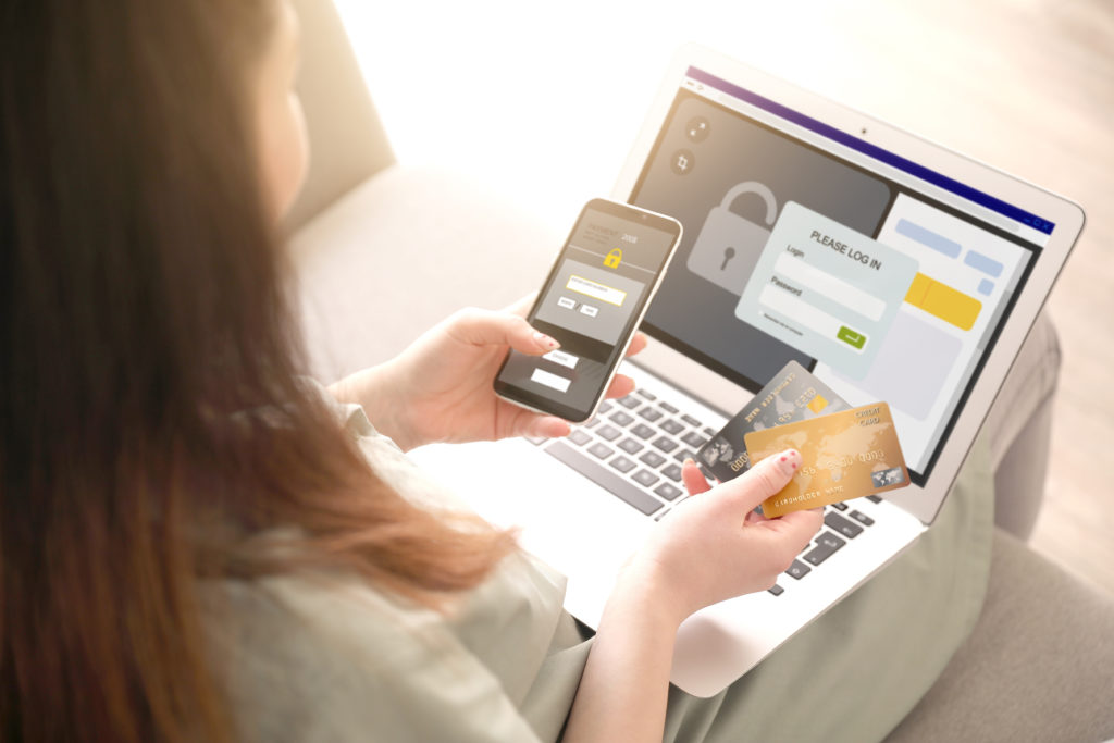 Woman with credit cards using a smartphone and a laptop.