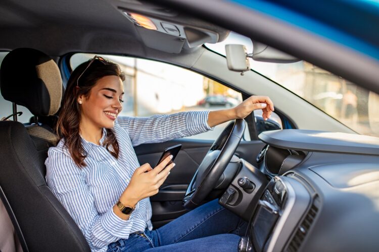 Young woman texting on her smartphone while driving