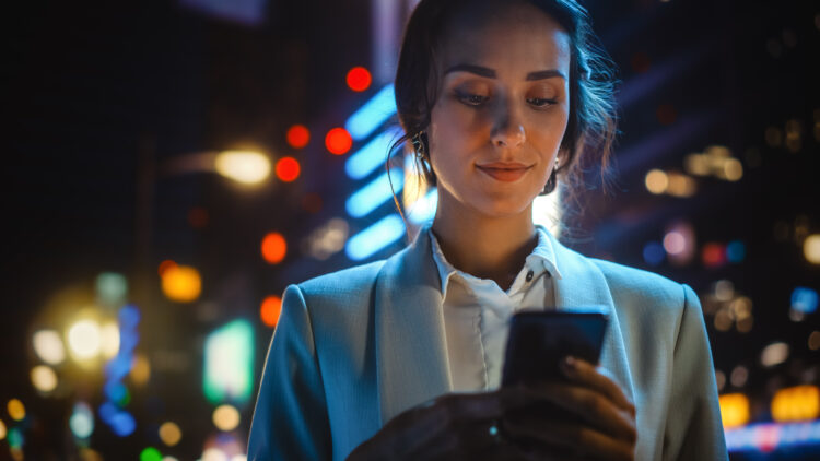 Beautiful woman using smartphone outdoor in urban street.