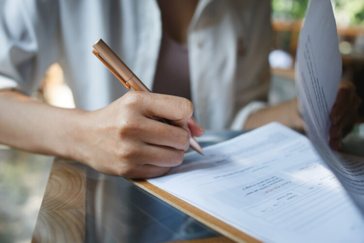 pen in female hand signing a document.