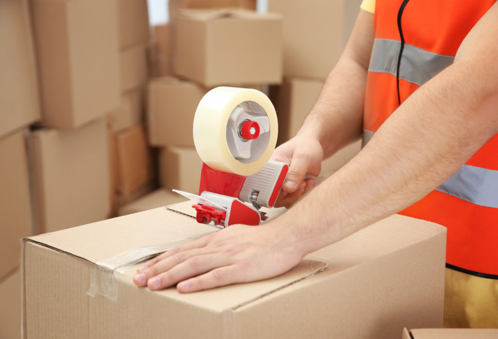 Sealing boxes using packing tape, warehouse.