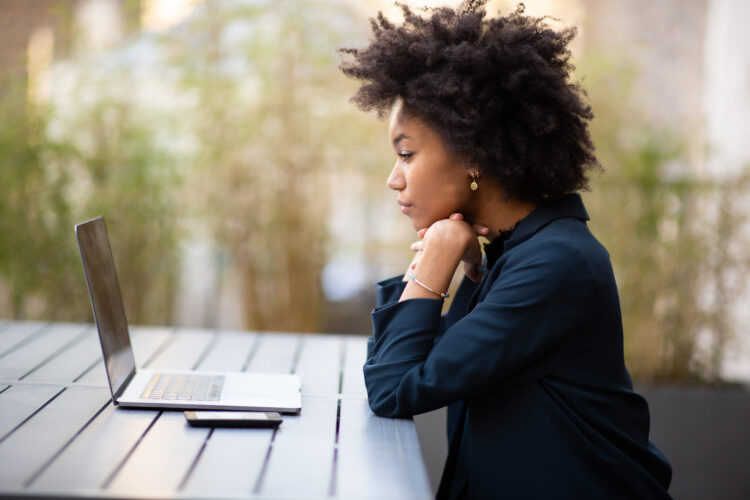 young african american business woman sitting with laptop outdoors