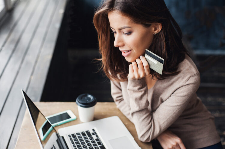 Young woman holding credit card and using laptop computer