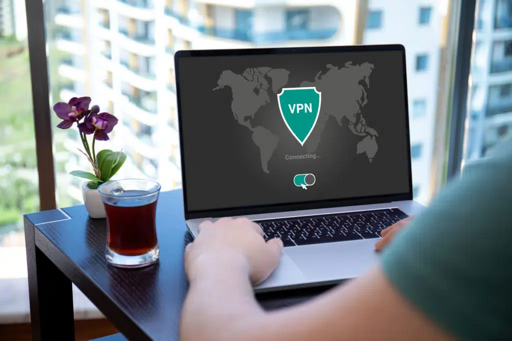 man uses app vpn on screen computer laptop in cafe