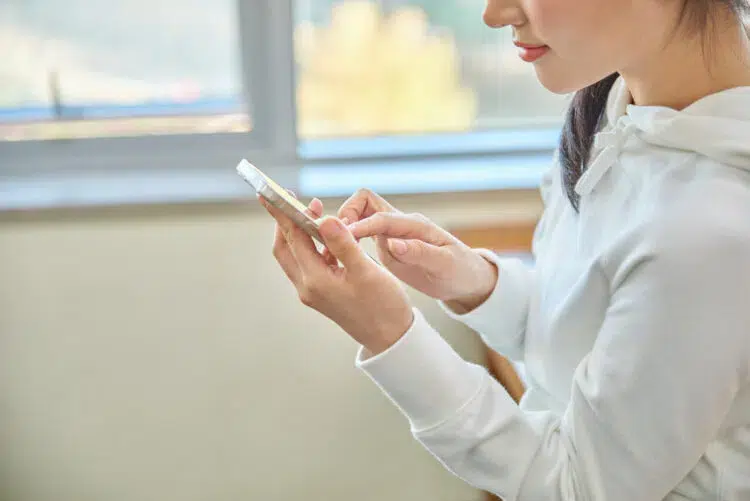 woman in white long sleeves using her phone indoors