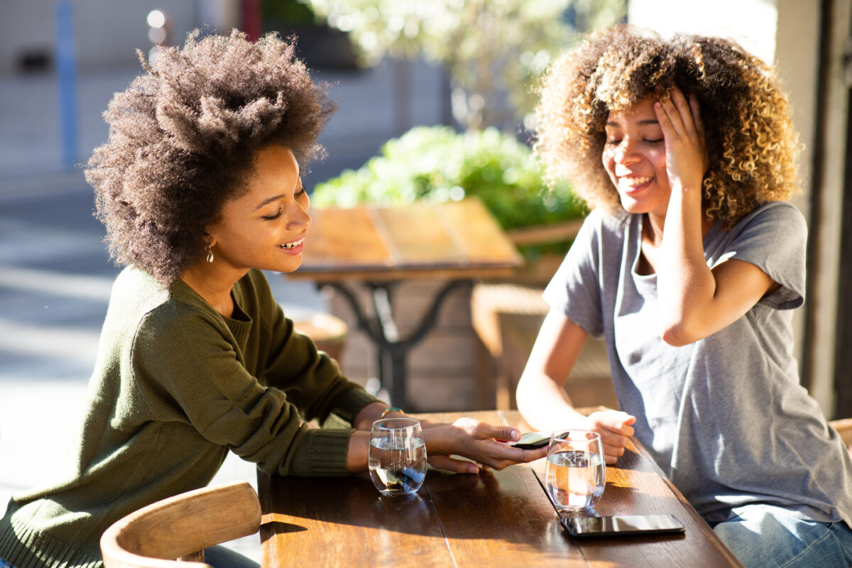 Women hanging out at outdoor cafe using their mobile phones.