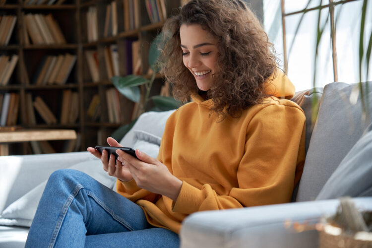 Young woman at home watching video online using smartphone.