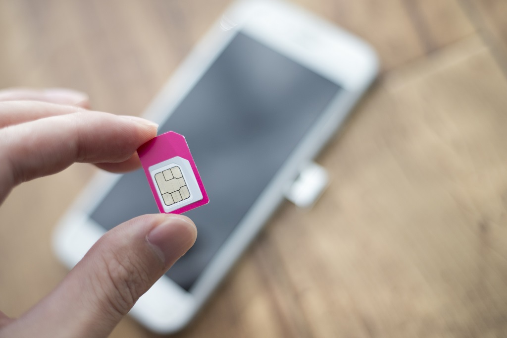 Female hand holding a pink sim card.