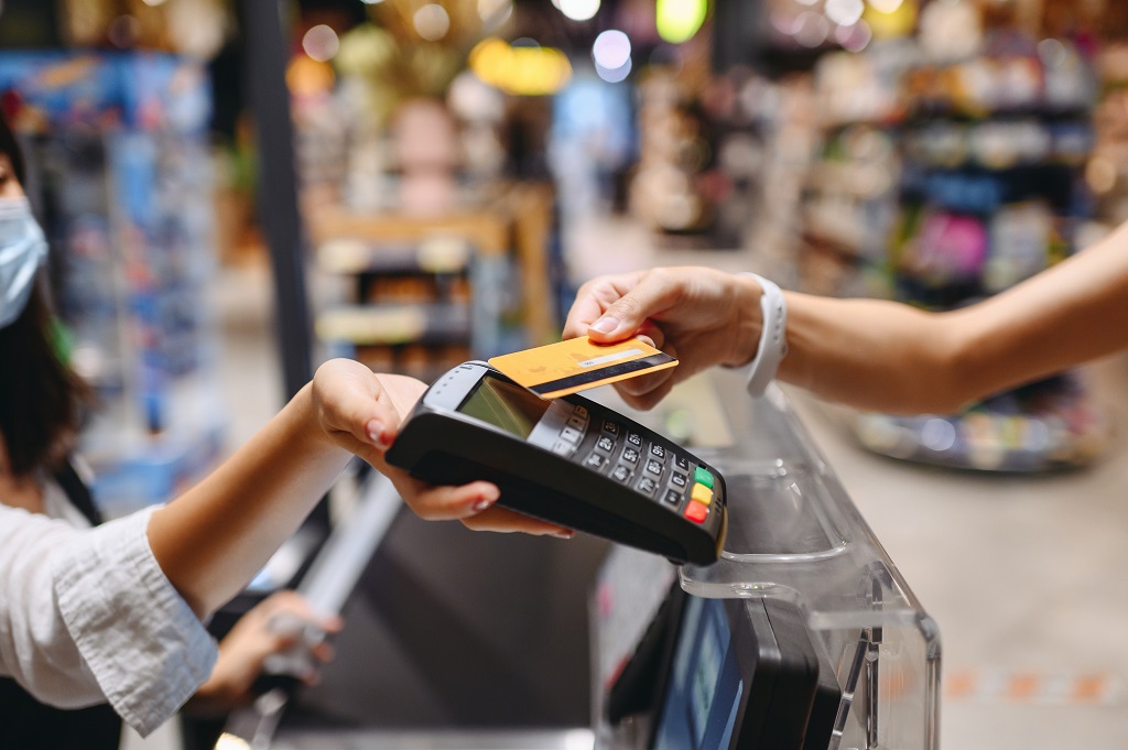 Woman shopping at supermaket put credit card to wireless modern bank payment terminal process.