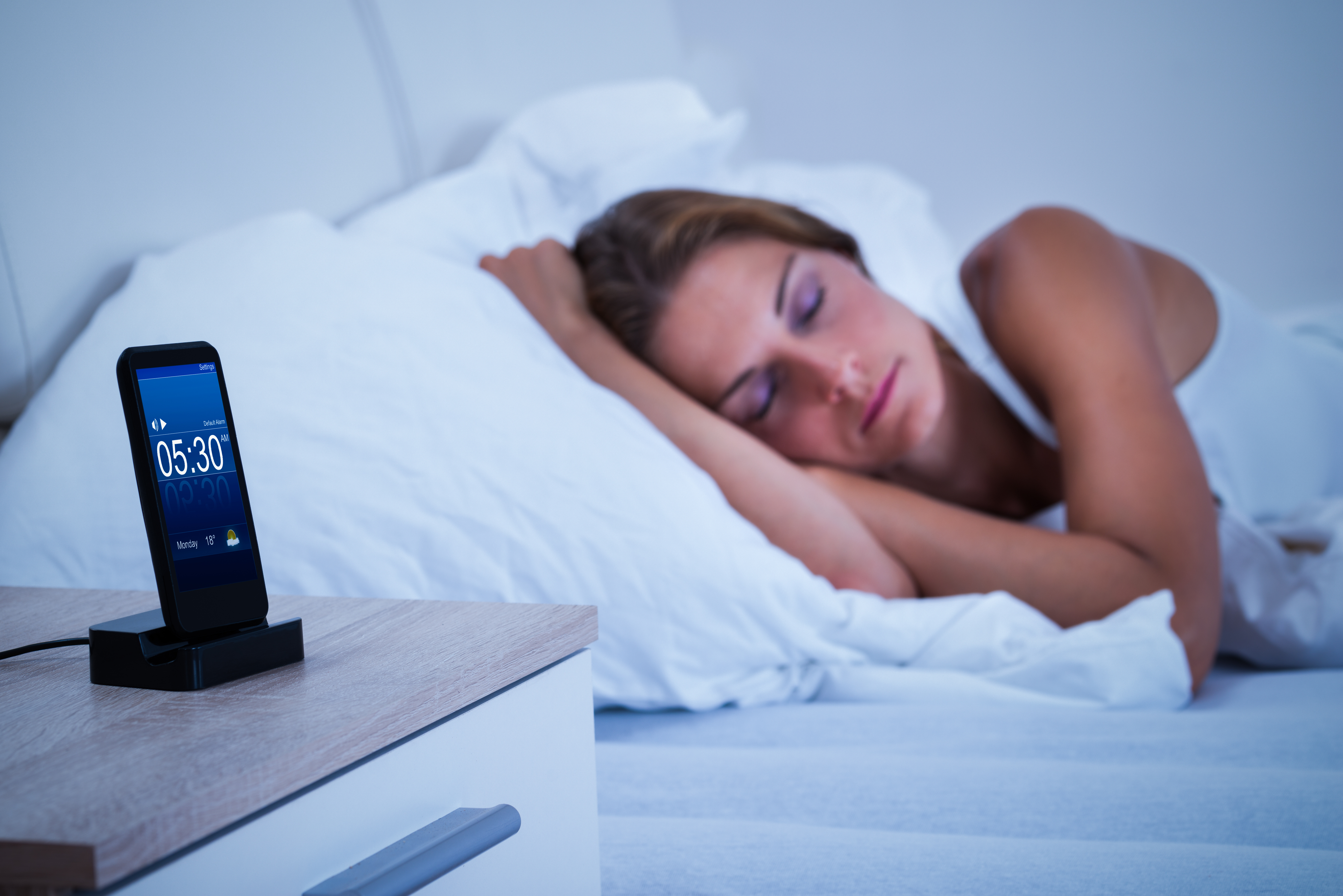 Sleeping woman with mobile phone on her desk.