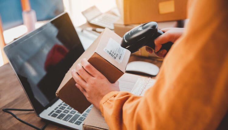 Delivery staff scanning cardboard box with barcode scanner 