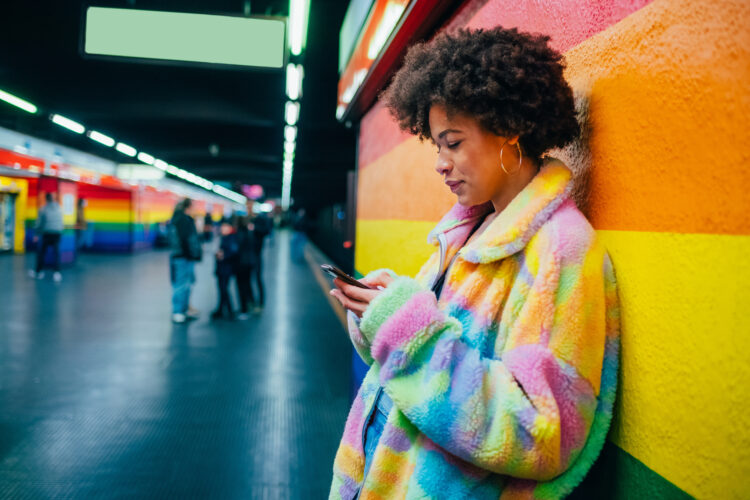 Young mixed race woman indoor metro station using smartphone