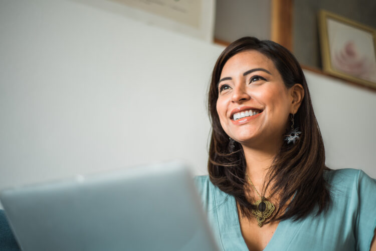 smiling latin woman while working on laptop at home