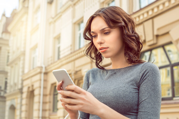 puzzled young female tourist walking using phone on the street