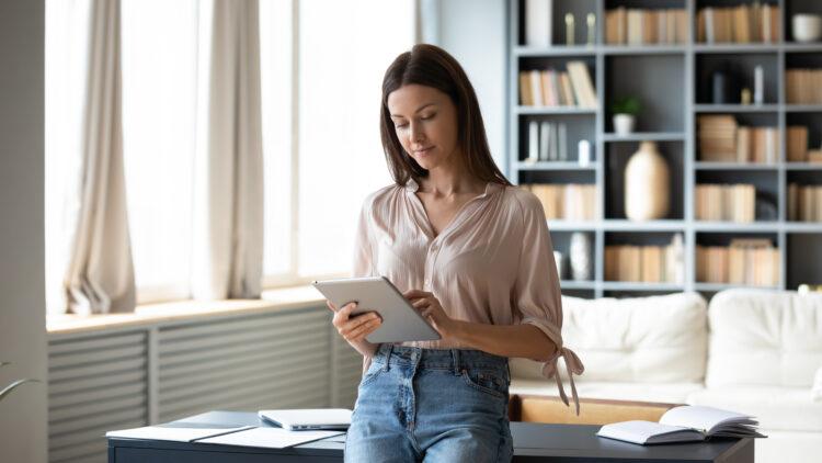 young woman using computer tablet, standing at home