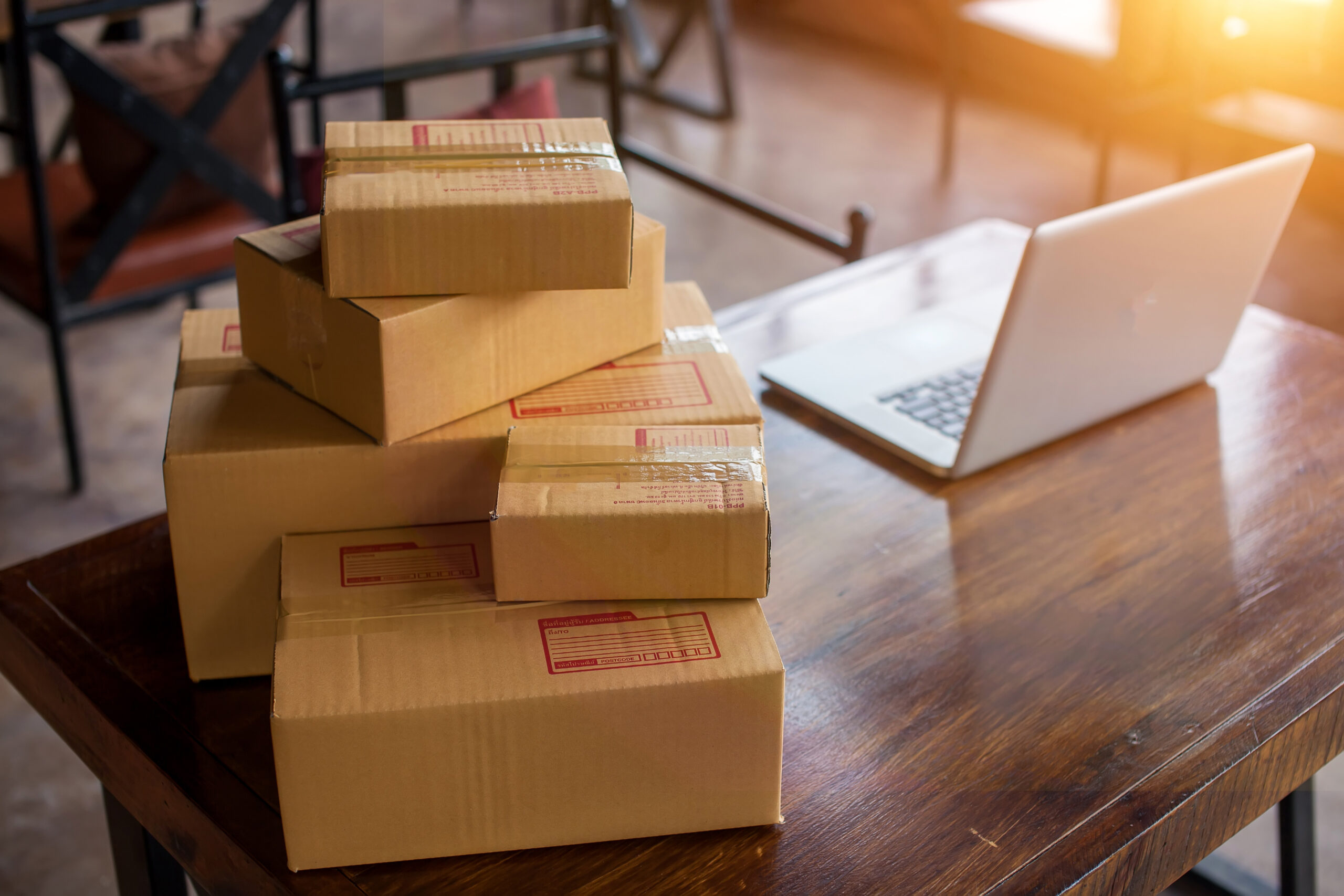 cardboard boxes with labels stacked on the table with a laptop
