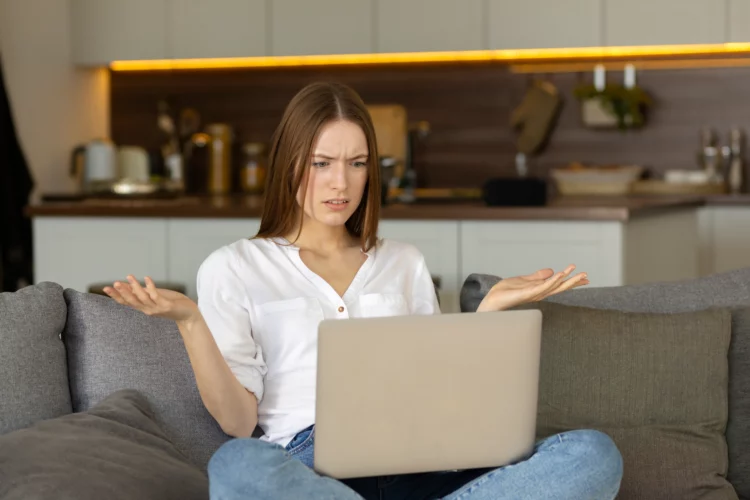 Dissatisfied young woman looking at laptop screen.