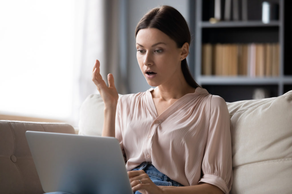 Shocked young woman looking at laptop screen.