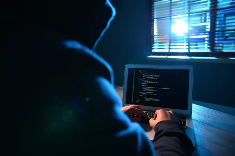 Hacker with laptop in dark room.