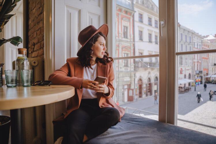 beautiful woman sitting in cafe looking out the big window
