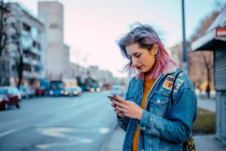 Hipster girl using phone at city street.