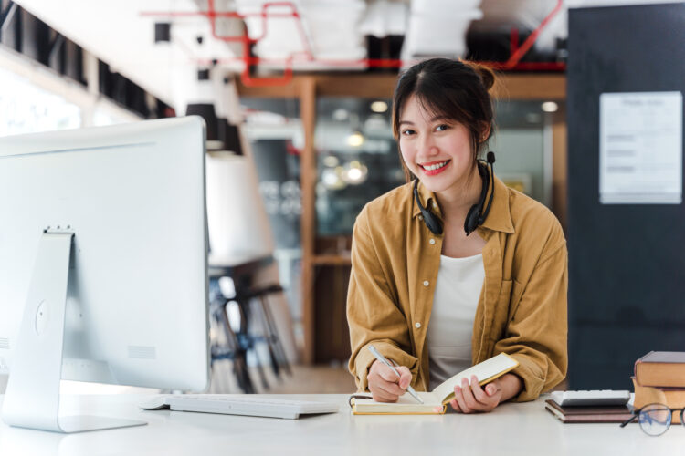 Beautiful smiling Asian employee working at desktop computer