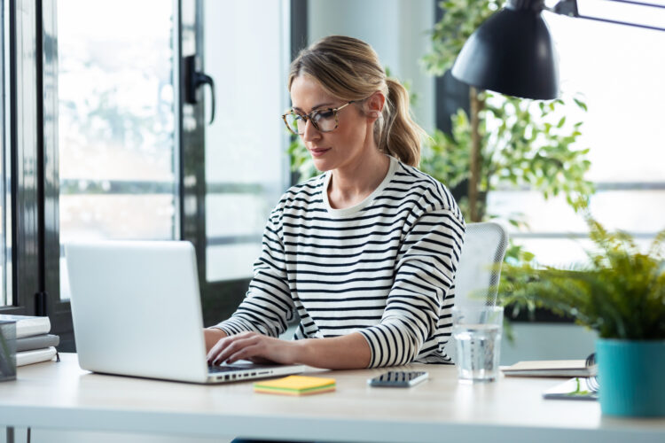 Wanita dewasa cantik bekerja sambil mengetik dengan laptop