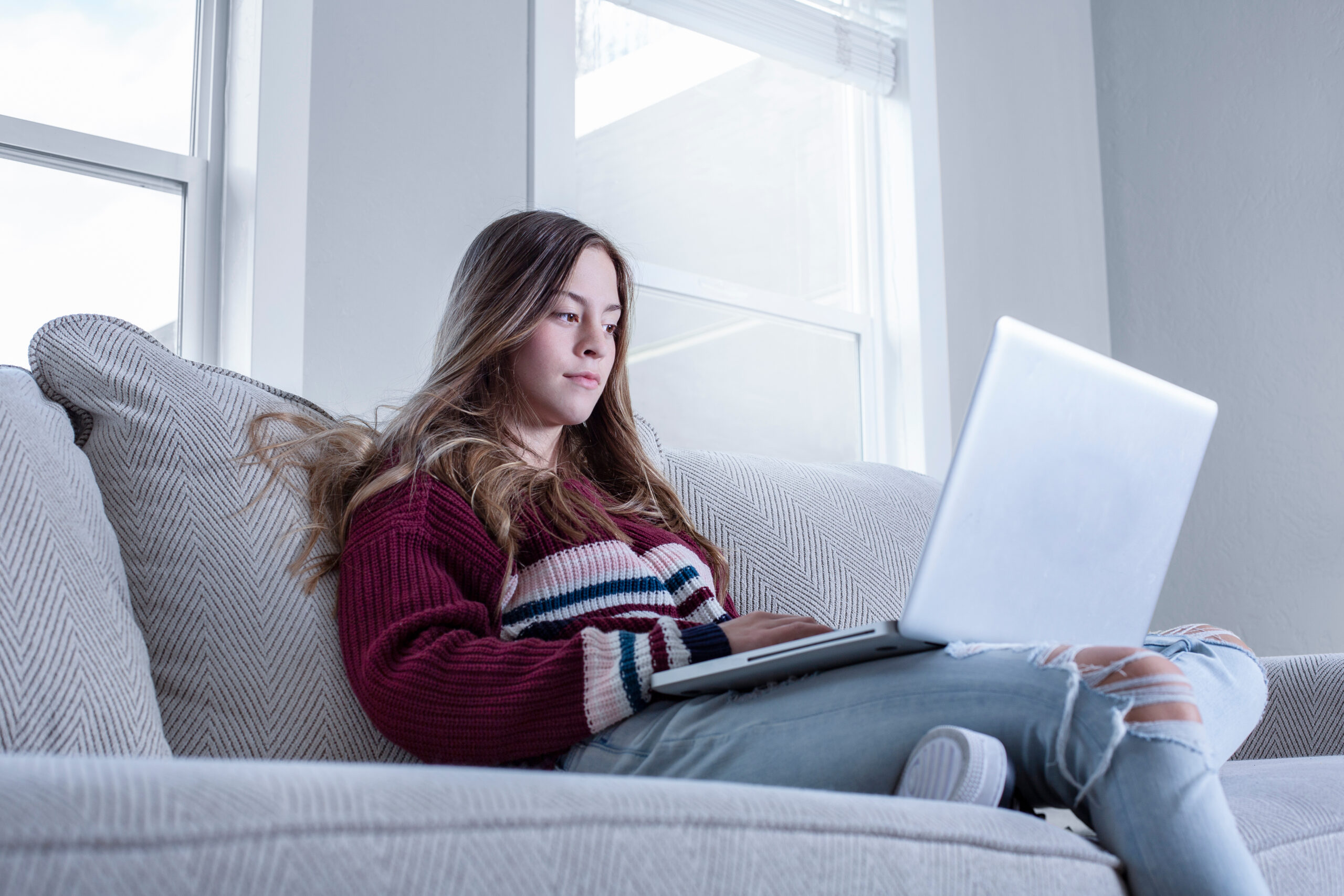 Teen female student studying on the couch doing school work from