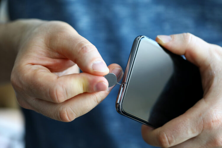 Male hands getting sim card slot of a smartphone out