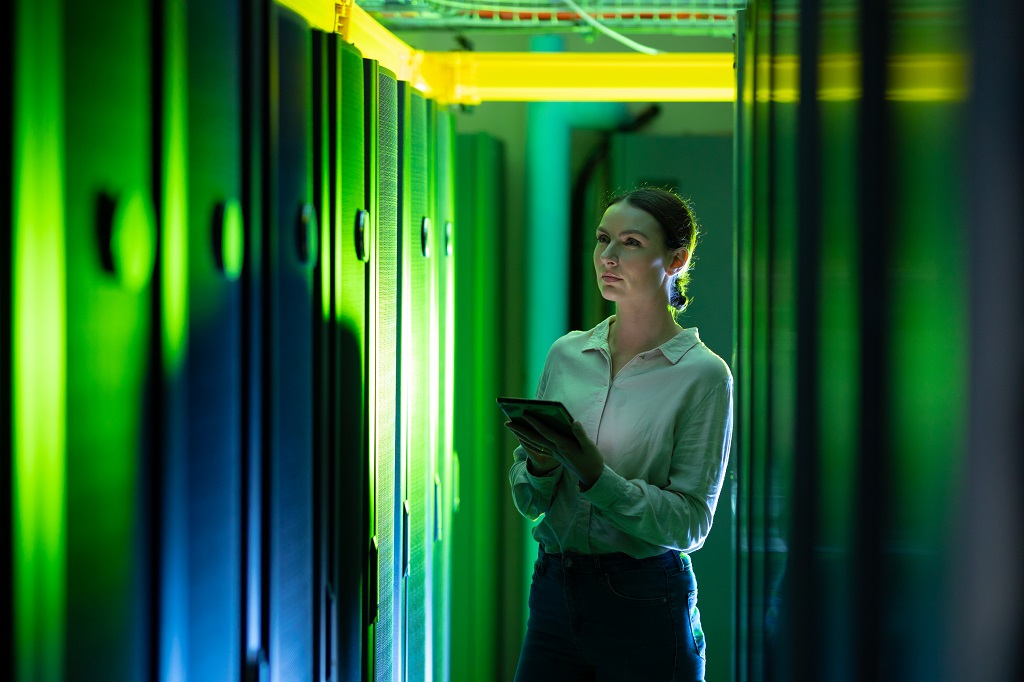 Female engineer using digital tablet while inspecting servers.