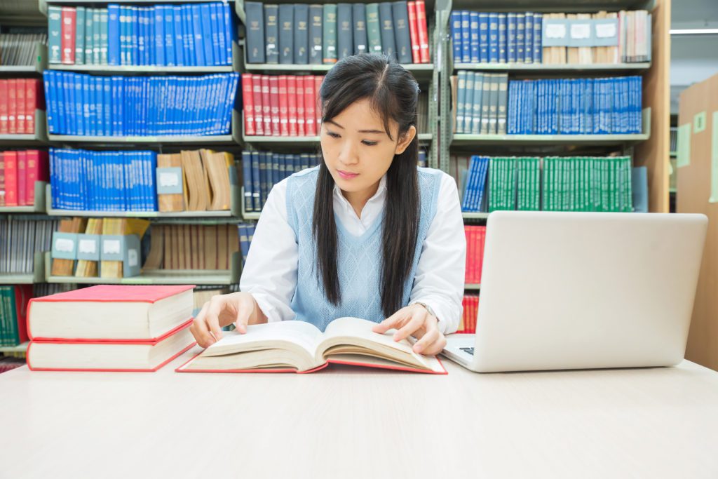 Student studying with books inside a college library.