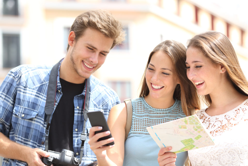 Happy tourists checking their phone and map.