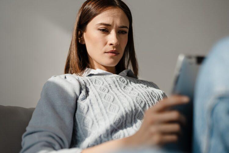 Middle aged woman using digital tablet frowning