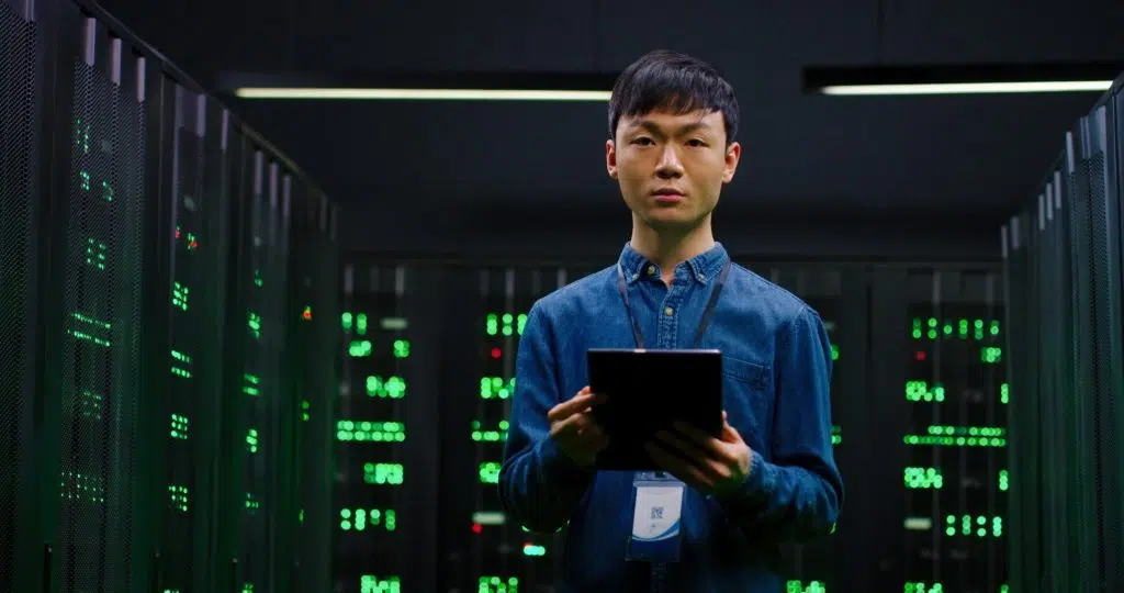 System administrator in a big data center standing among servers.