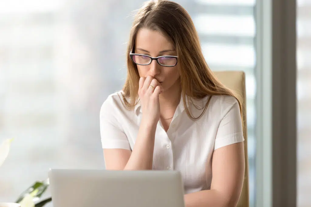Female office worker looks anxiously on the laptop
