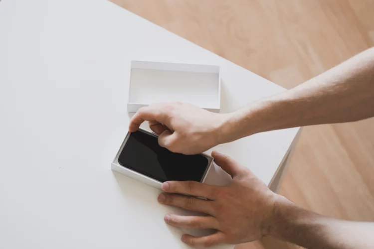 a person holds the new smartphone box and unpack it