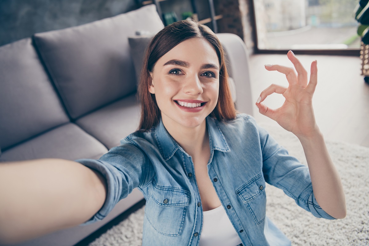 Cheerful young woman taking a selfie in a manner so that the selfies aren't backwards.