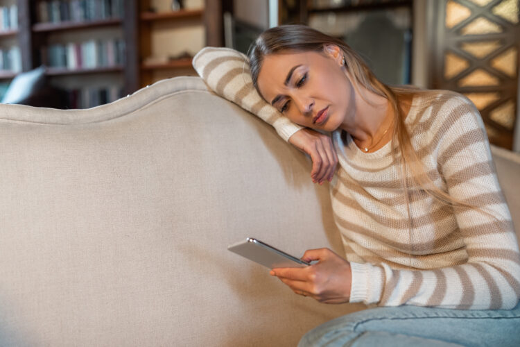 Sad lady using cellphone, looking at screen