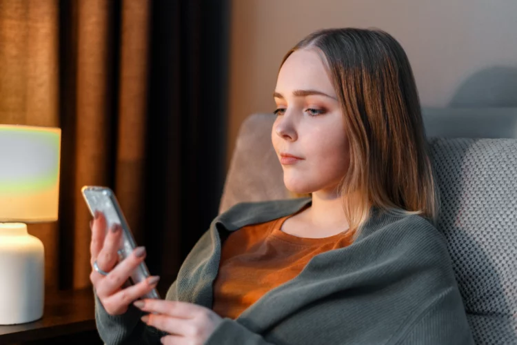  Indifferent young woman in home clothes use smartphone