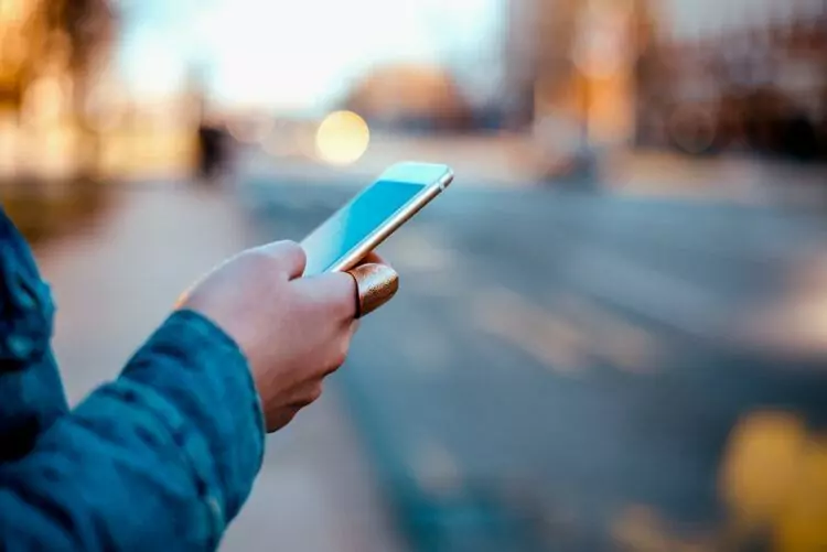 female hand using phone in the city street.