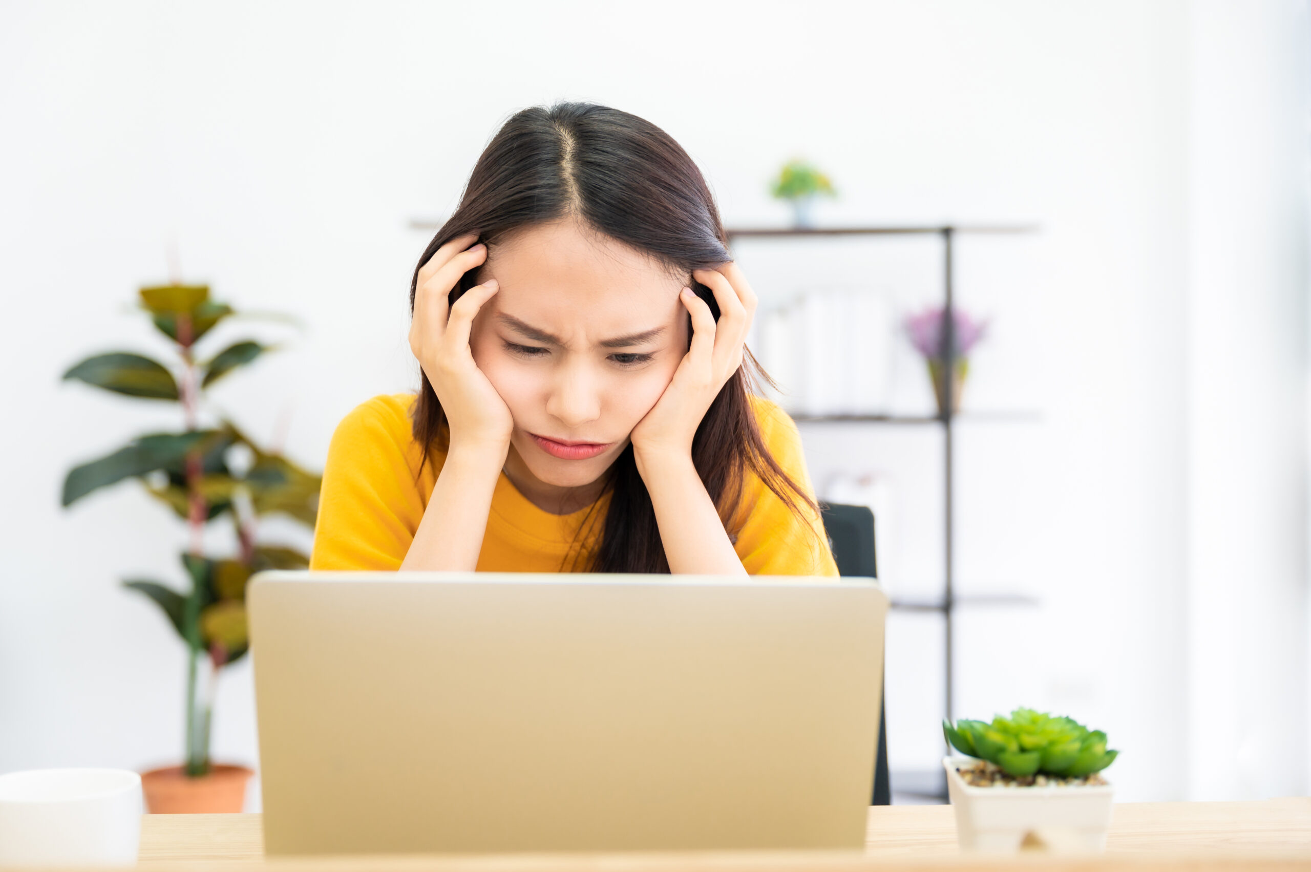 young woman using laptop with serious, irritated expression 