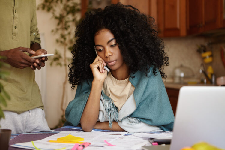 Young afro american woman looking worried talking on mobile phone