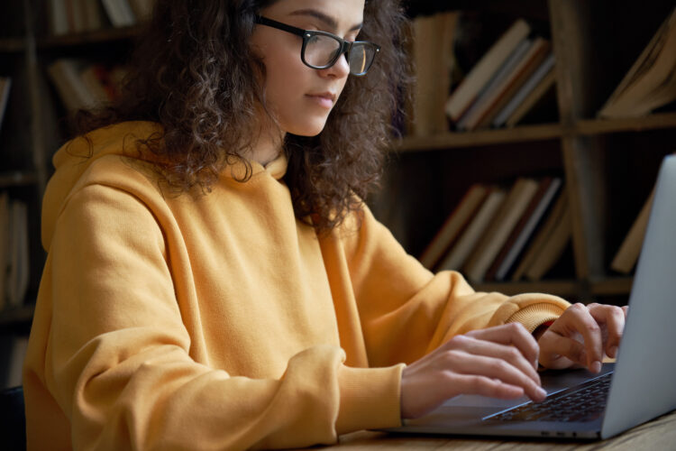 Serious student working on her laptop in the library