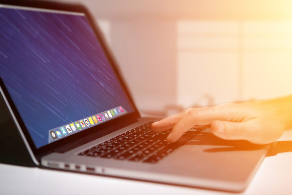 Hand typing on a keyboard of laptop with operating system screen on background